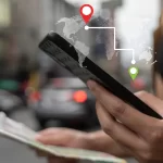 Mulher usando smartphone para verificar mapas com GPS, simbolizando o uso de tecnologia de navegação em viagens.